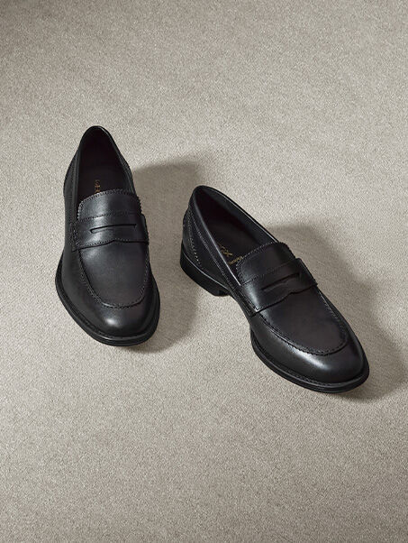 Elegant men's black leather loafers side by side on beige carpet, left shoe slightly forward and right shoe behind | GEOX | GEOX
